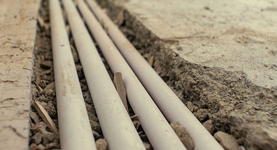Exposed pipes laid in a concrete floor trench construction site.