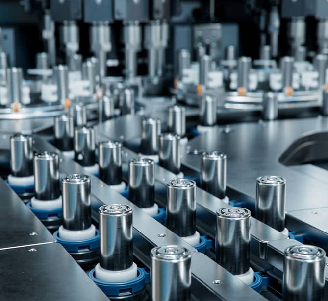 Assembly line with rows of cylindrical battery cells in a manufacturing facility.