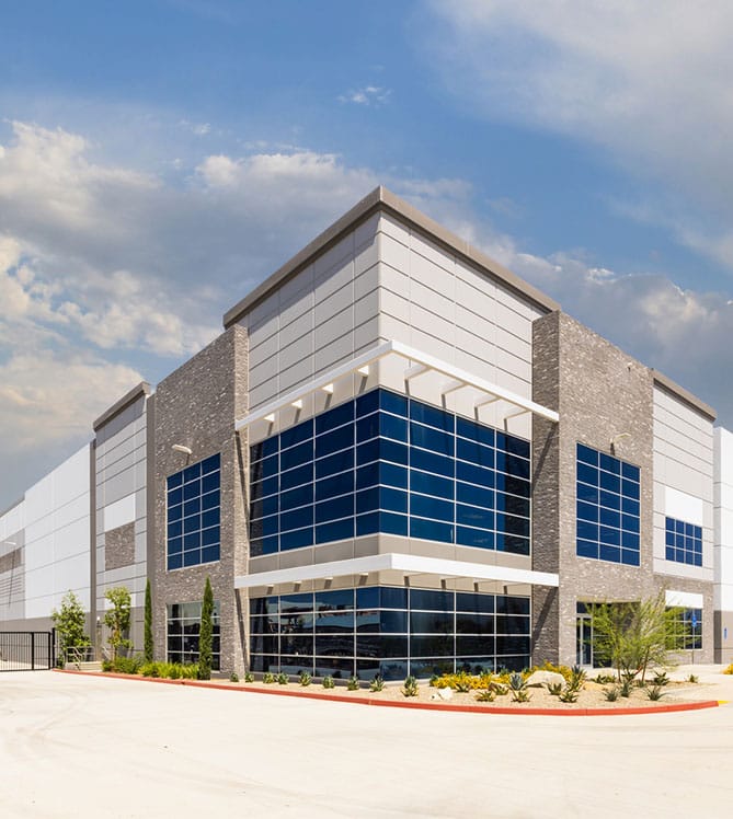 Modern industrial building with large blue windows under a partly cloudy sky.