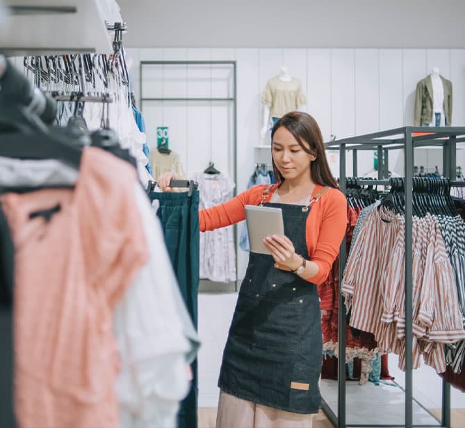 A woman in a retail store checks inventory on a tablet.