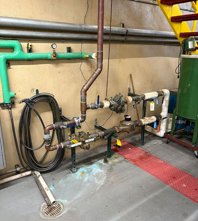 Industrial piping system with gauges and valves in a utility room.