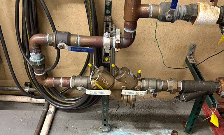 Industrial plumbing system with connected pipes and valves against a wall.