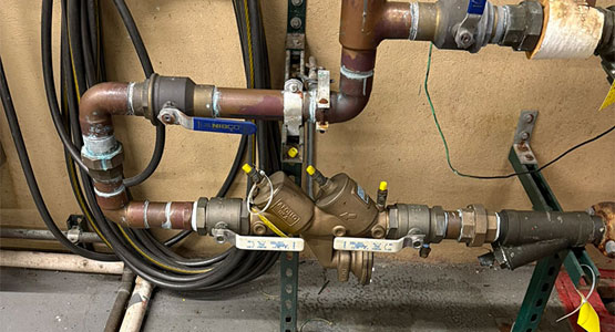 Complex piping system with valves and gauges against a beige wall.