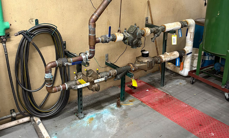 Industrial plumbing setup with various pipes and valves in a maintenance room.