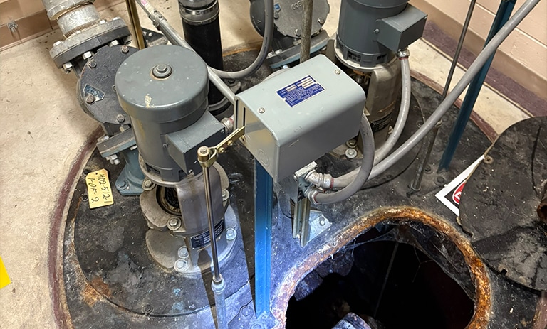 Industrial pump equipment with pipes and gauges in a maintenance setting.